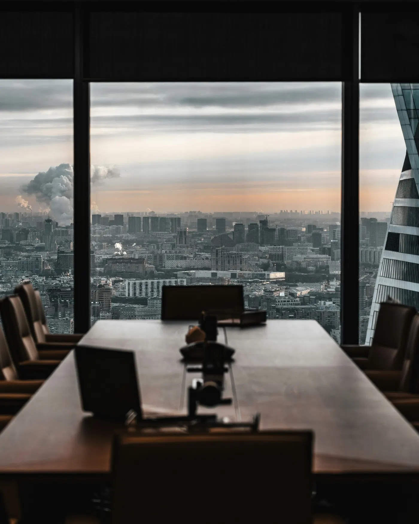 Empty boardroom table overlooking a city skyline at dusk
